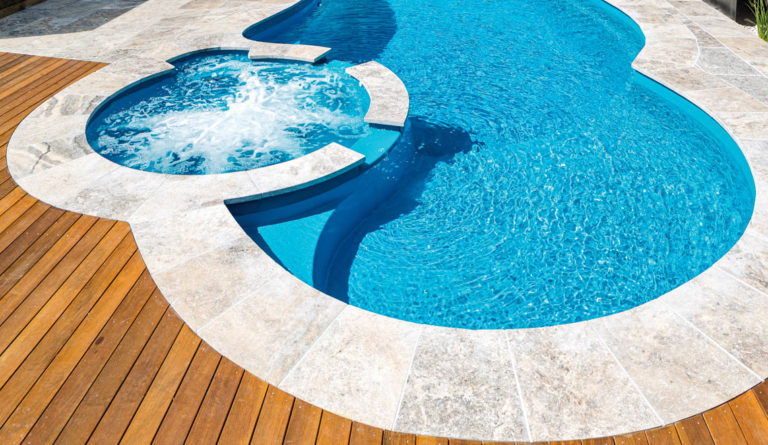 The Allure fiberglass pool built-in spa spillover close-up in Crystal Blue
