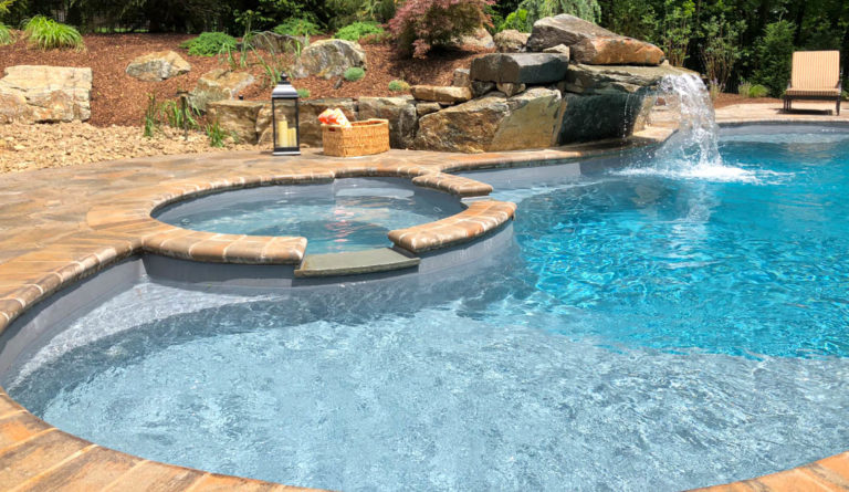 The Allure 40 fiberglass pool spa spillover with rock surround in Graphite Grey