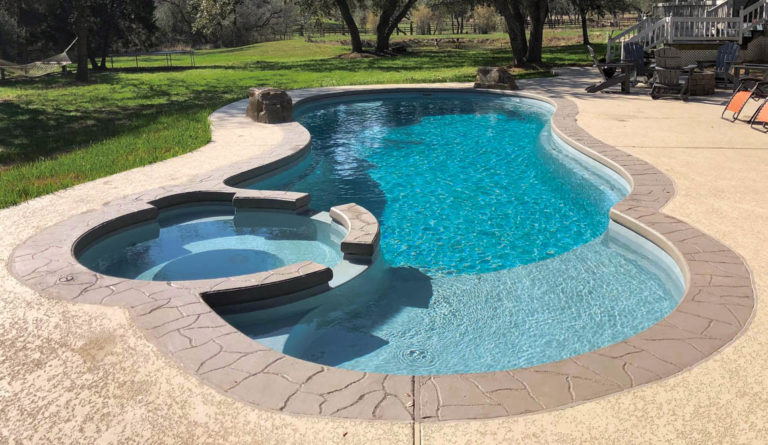 The Allure fiberglass pool in Silver Grey with rock features and built-in spa