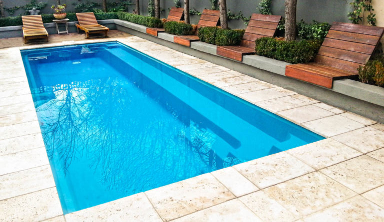 The Harmony 23 compact fiberglass pool in Crystal Blue with clean open patio surround