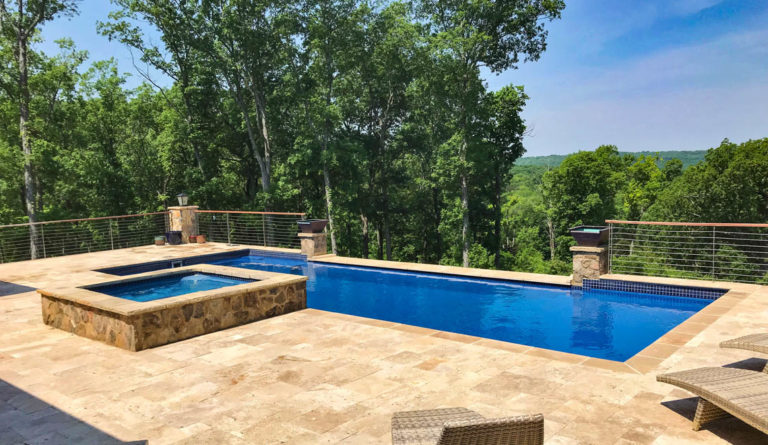 The Pinnacle fiberglass pool in Sapphire Blue installed on waterfront lot with raised stone wall surround
