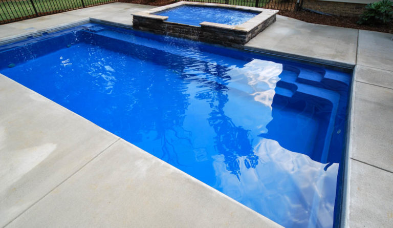 The Reflection fiberglass pool bench seat and entry steps detail with raised spa in Sapphire Blue