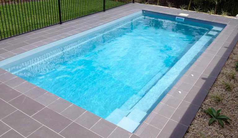 The Reflection fiberglass pool in Silver Grey with iron fence and grey slate patio surround