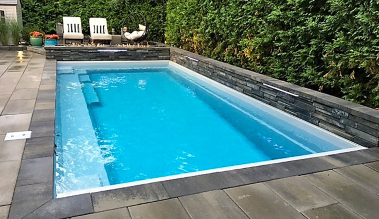 The Reflection fiberglass pool in Silver Grey with raised retaining wall and open backyard