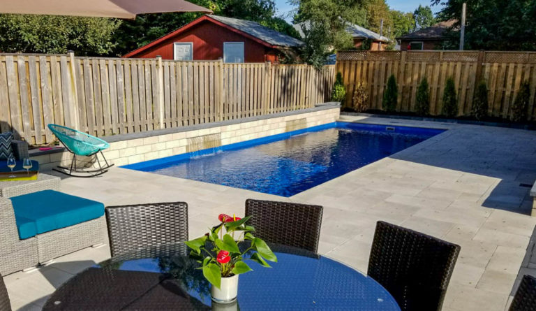 The Reflection fiberglass pool in Silver Grey with fenced backyard and outdoor patio furniture