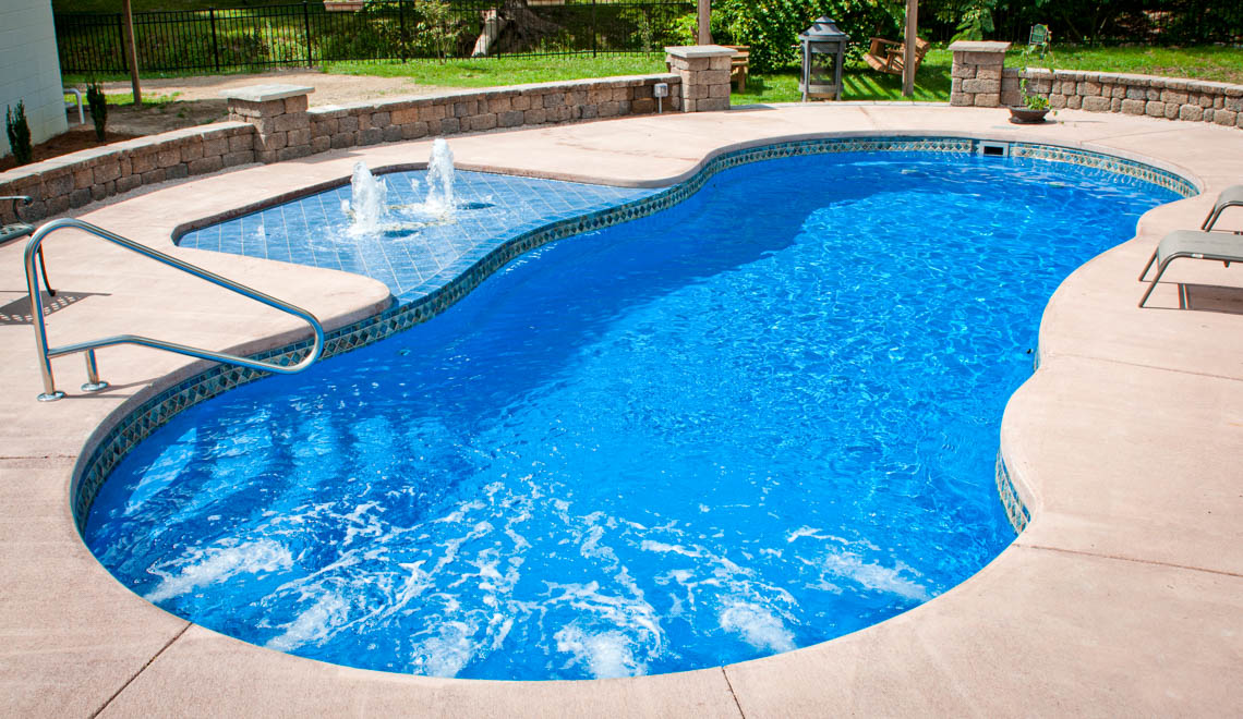 Leisure Pools Riviera composite fiberglass freeform swimming pool with large wrapped bench sat