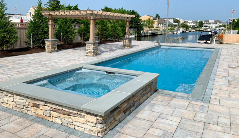 The Supreme 40 fiberglass pool in Silver Grey with raised spa and natural stone cladding