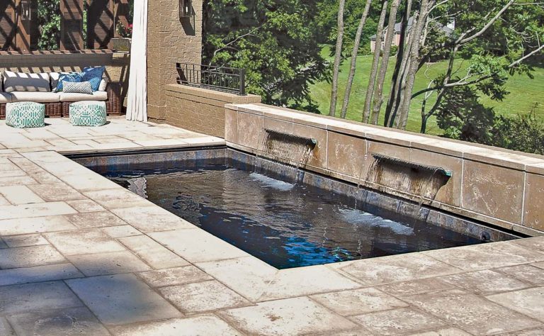 The Palladium Plunge compact fiberglass plunge pool in Ebony Blue with travertine paver surround