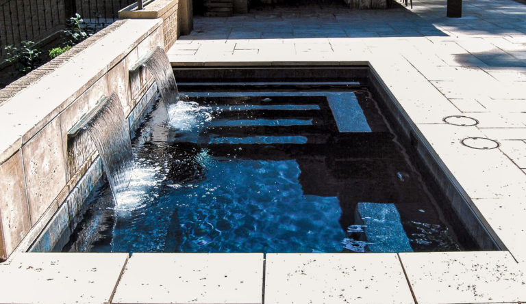 The Palladium Plunge fiberglass pool lounge seating and entry steps with waterfall feature in Ebony Blue