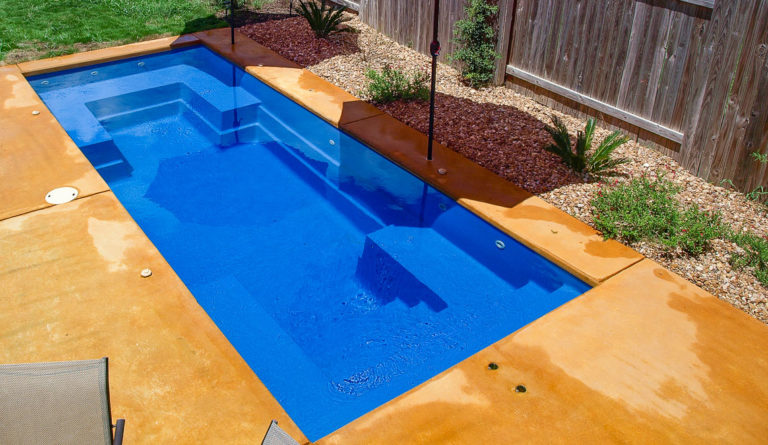 The Palladium Plunge compact fiberglass pool in Sapphire Blue with decorative landscaping and patio