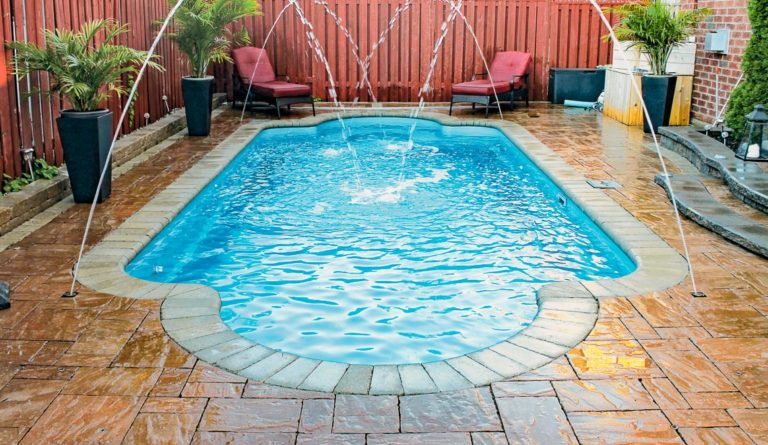 Leisure Pools Roman fiberglass pool in Crystal Blue with poolside seating and classical design