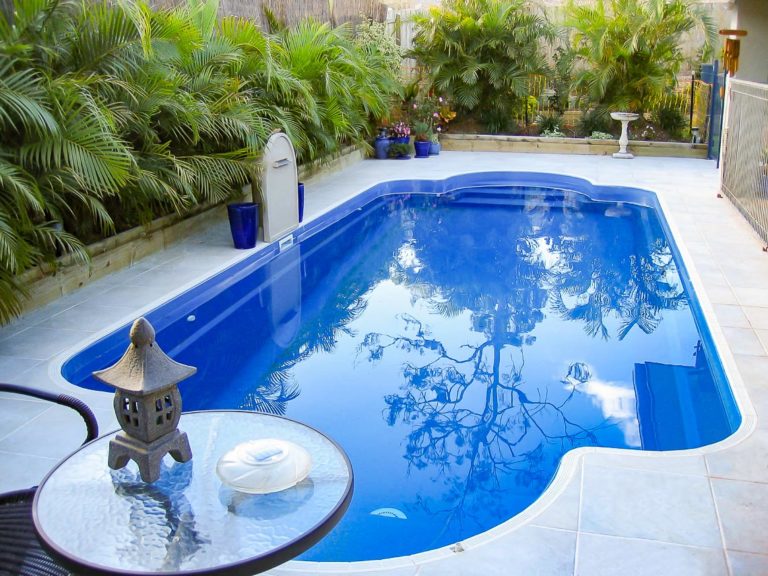Leisure Pools Roman fiberglass pool in Sapphire Blue with tropical landscaping and spa nook