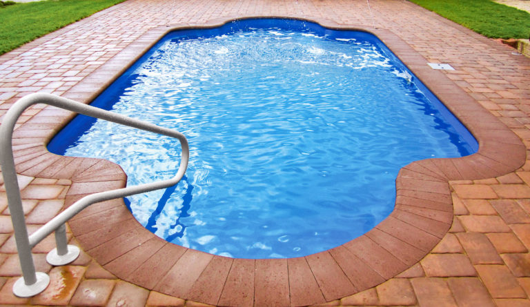 The Roman fiberglass pool in Sapphire Blue with classical rounded ends and terracotta paver surround