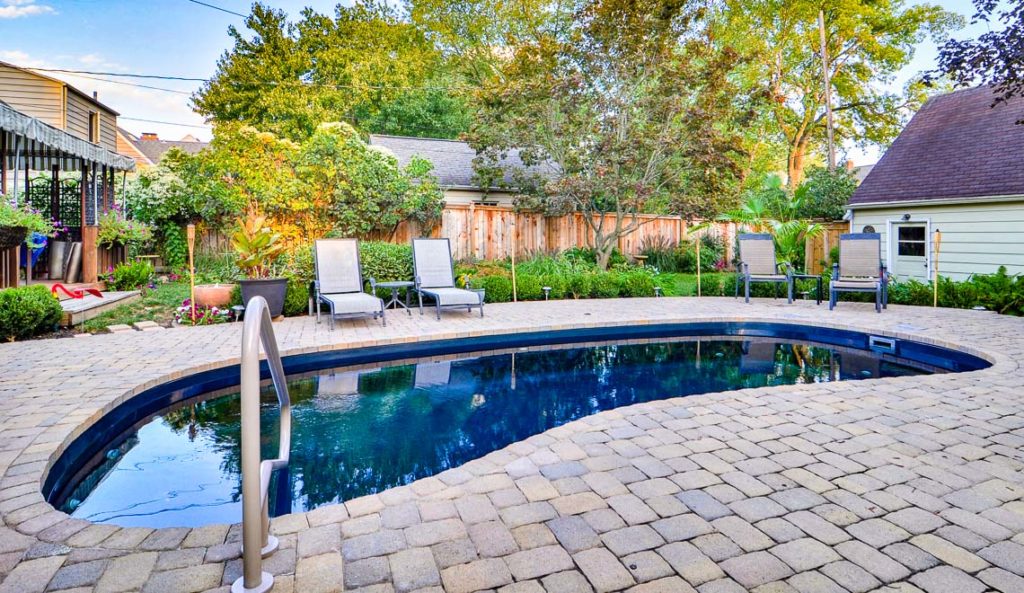 Leisure Pools Tuscany fiberglass pool in Ebony Blue with paver patio and outdoor seating