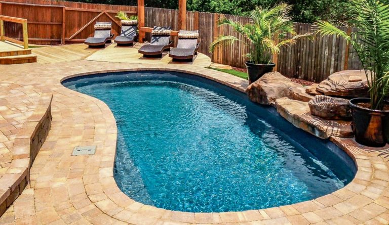 The Tuscany fiberglass pool in Graphite Grey with poolside lounge chairs and rock feature