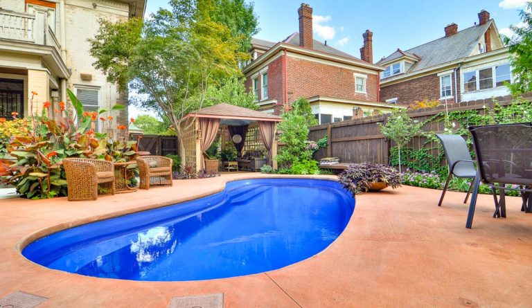 The Tuscany kidney-shaped fiberglass pool with backyard pergola and patio surround