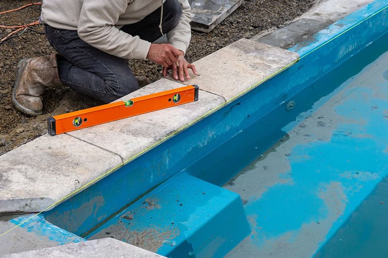 Installing coping on a Leisure Pools fiberglass swimming pool