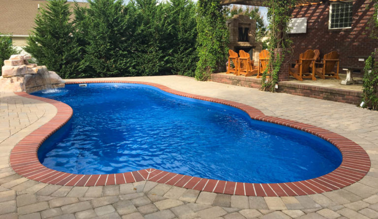 The Eclipse fiberglass pool in Sapphire Blue with terracotta paver surround and open backyard