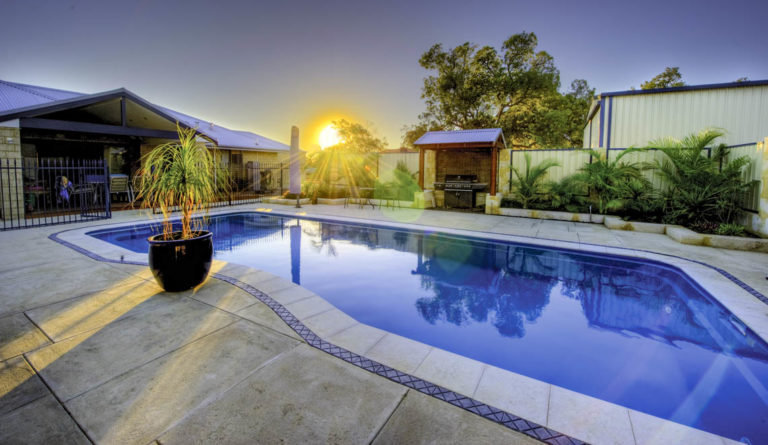 Leisure Pools Moroccan fiberglass pool in Crystal Blue with dramatic dusk backdrop