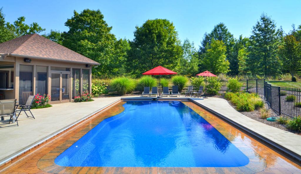 Leisure Pools Moroccan fiberglass pool in Sapphire Blue with open backyard and poolside umbrella