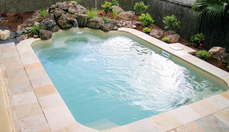 The Courtyard Roman small inground fiberglass pool in Diamond Sand with stone surround