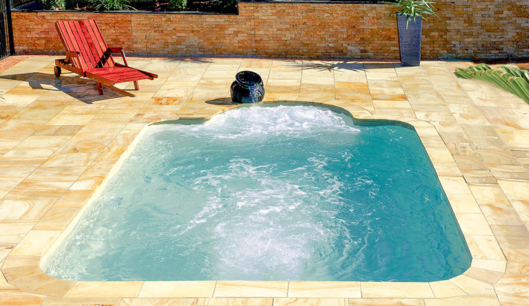The Courtyard Roman fiberglass pool with optional swim jet system in Diamond Sand