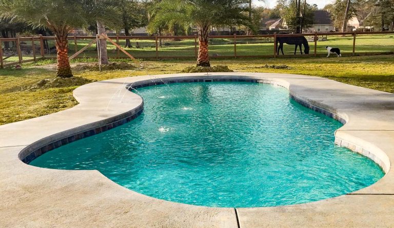 Leisure Pools Eclipse fiberglass pool with open backyard installation in Aquamarine gel coat finish