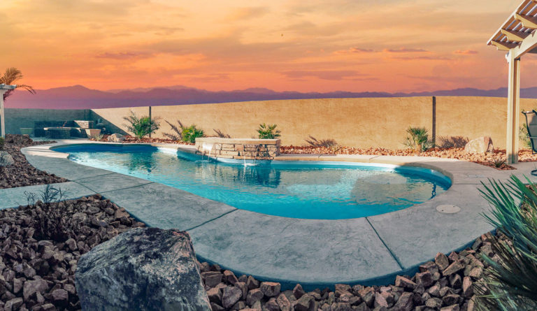 The Eclipse inground fiberglass pool at dusk with dramatic sunset backdrop in Crystal Blue
