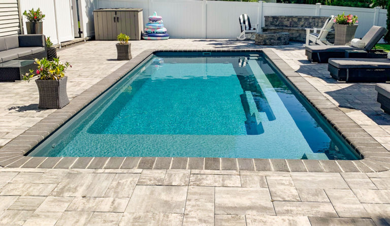 The Reflection fiberglass pool generous splash deck and full length bench seat in Graphite Grey
