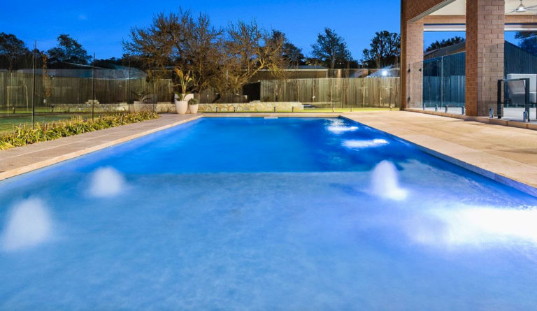 Leisure Pools Reflection fiberglass pool in Silver Grey with open fenced backyard installation