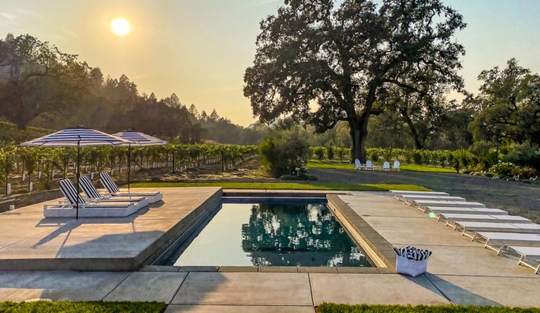 The Summit fiberglass pool in Graphite Grey with open backyard and golden dusk sky backdrop