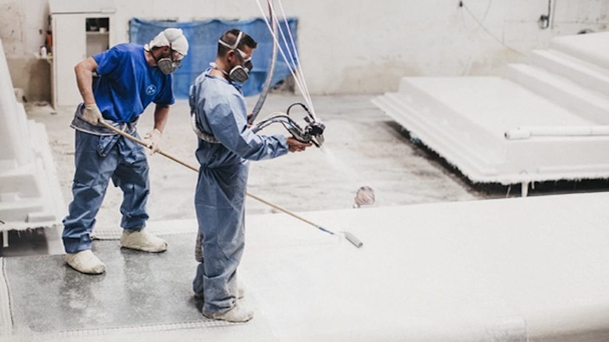 Fiberglass Pool Manufacturing Leisure Pools factory workers spraying an inground fiberglass pool