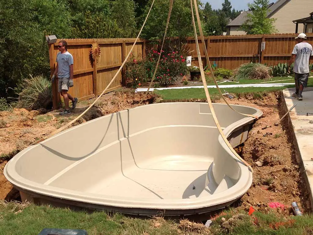 a fiberglass pool has been lowered into a dug hole