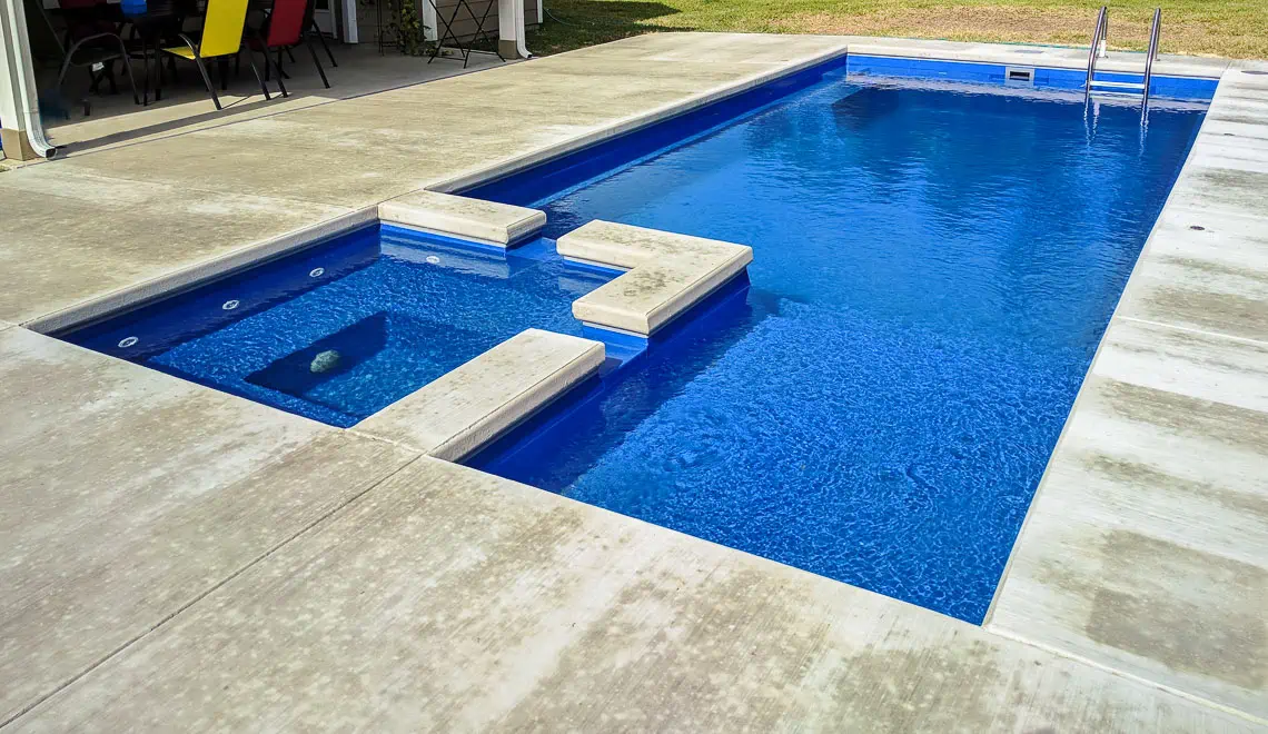 Leisure Pools Limitless fiberglass pool model with built-in spa and tanning ledge