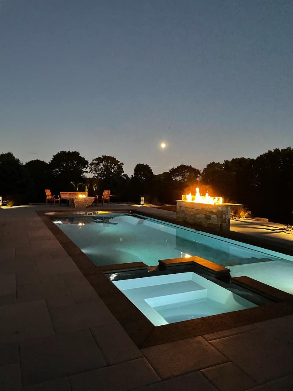 A fiberglass inground swimming pool with night illumination