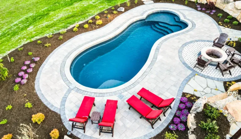 The Eclipse fiberglass pool splash deck with poolside lounge chairs in Graphite Grey