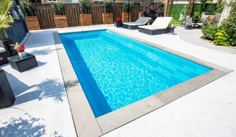 The Reflection fiberglass pool in Crystal Blue with clean concrete surround and open backyard