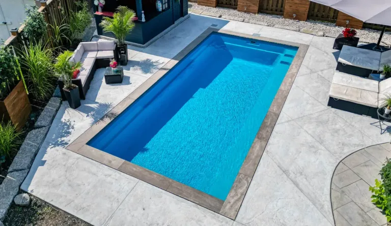 The Reflection rectangular fiberglass pool in Crystal Blue with brick paver surround