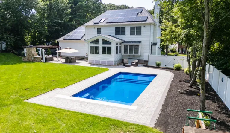 The Pinnacle fiberglass pool with white home and rooftop solar installation