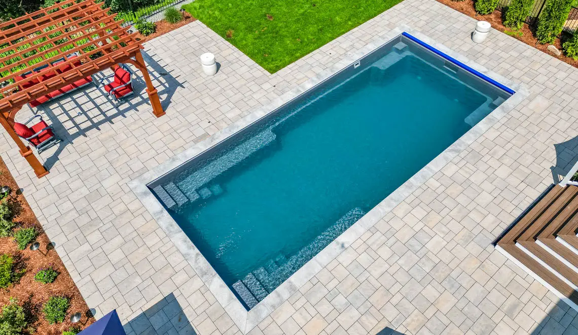 Leisure Pools Supreme composite fiberglass swimming pool with unobstructed swim channel in Graphite Grey