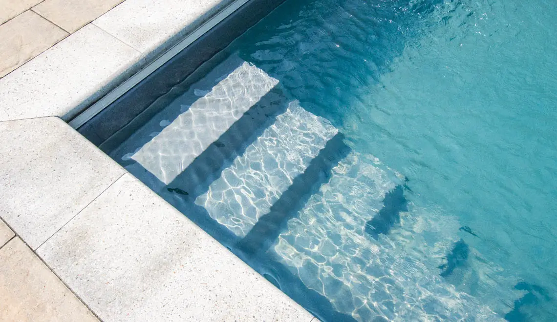 Leisure Pools Supreme composite fiberglass swimming pool with generous bench seats in Graphite Grey