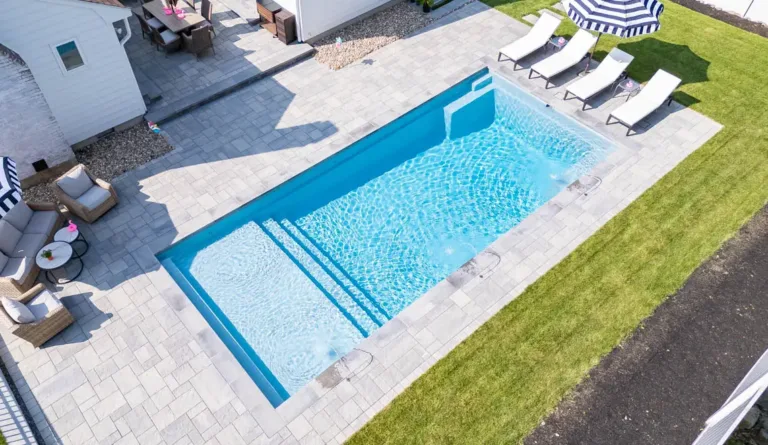 The Pinnacle fiberglass pool with full width entry step and poolside lounge chairs