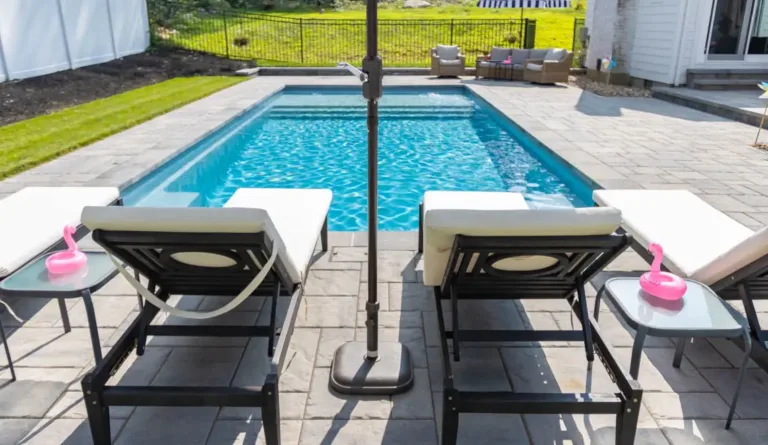 The Pinnacle fiberglass pool splash deck with outdoor umbrella and patio furniture