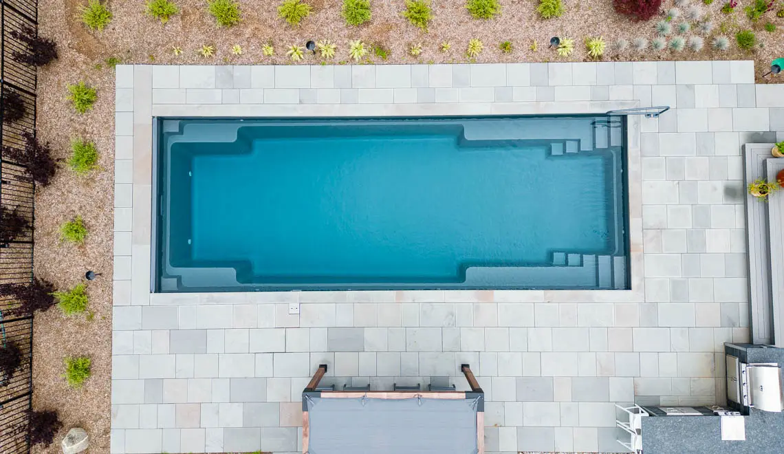 Leisure Pools Supreme inground fiberglass swimming pool with deep end swimout and bench seats in Graphite Grey