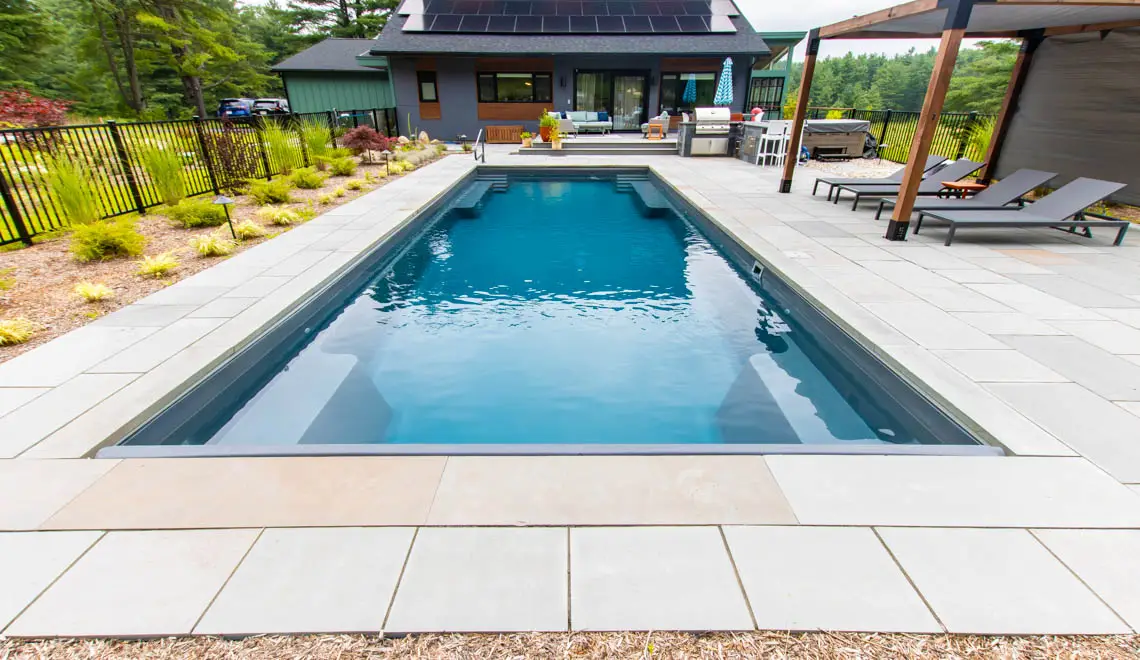 The Supreme 40 fiberglass pool in Graphite Grey with modern home and clean patio surround