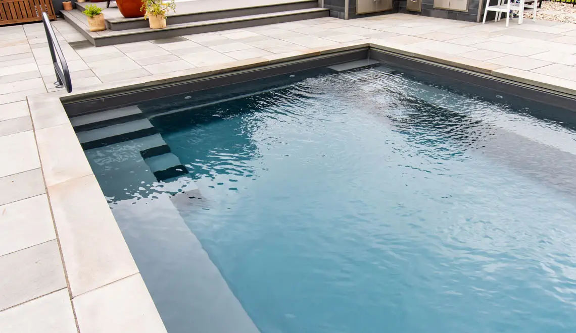 Leisure Pools Supreme inground fiberglass swimming pool with unobstructed swim channel in Graphite Grey