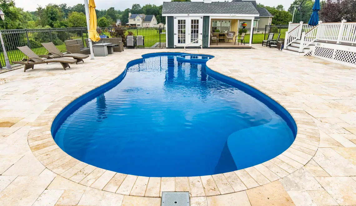 Leisure Pools Allure inground freeform swimming pool with built-in spa and splash deck in Sapphire Blue