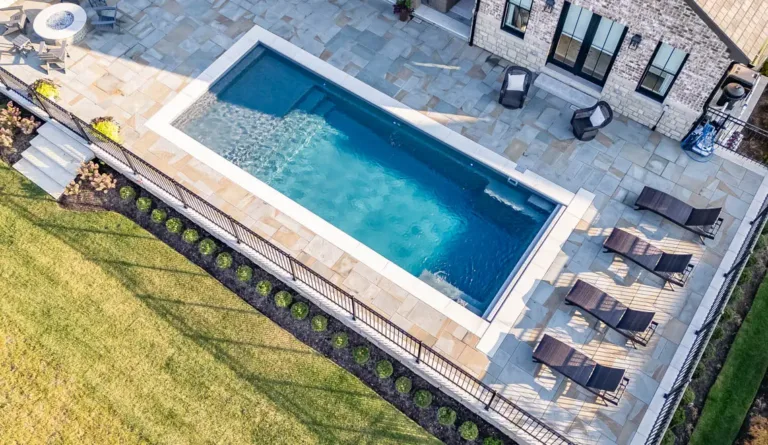 The Pinnacle rectangular fiberglass pool aerial crop showing stone tile border detail in Granite Gray
