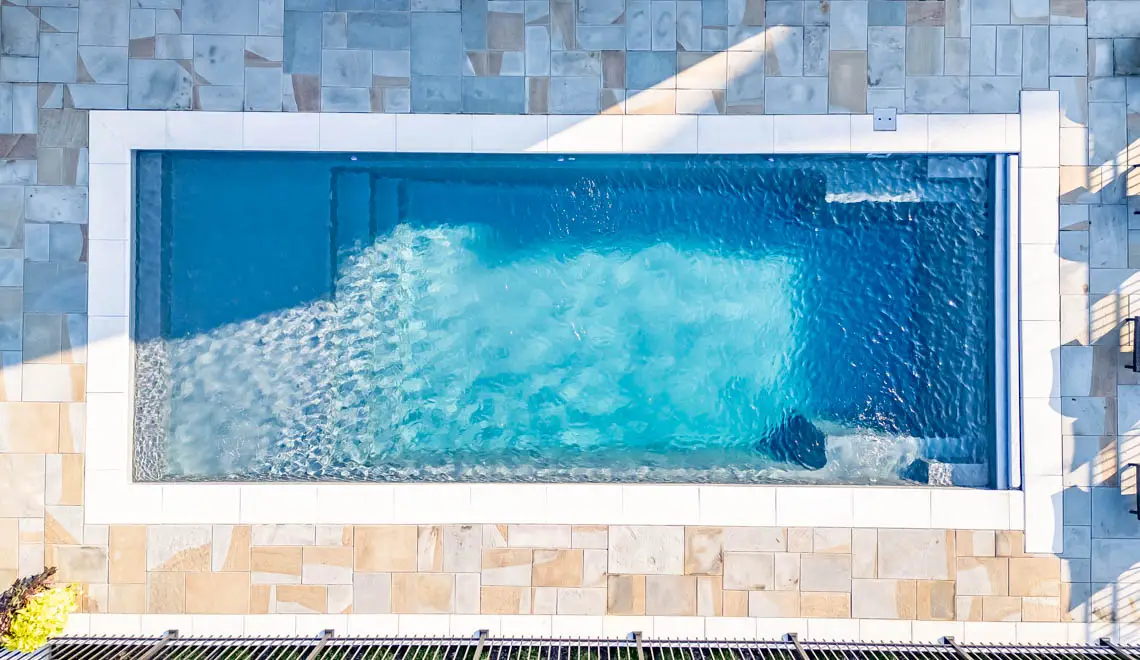 Leisure Pools Pinnacle inground fiberglass swimming pool with full-width entry step in Silver Grey