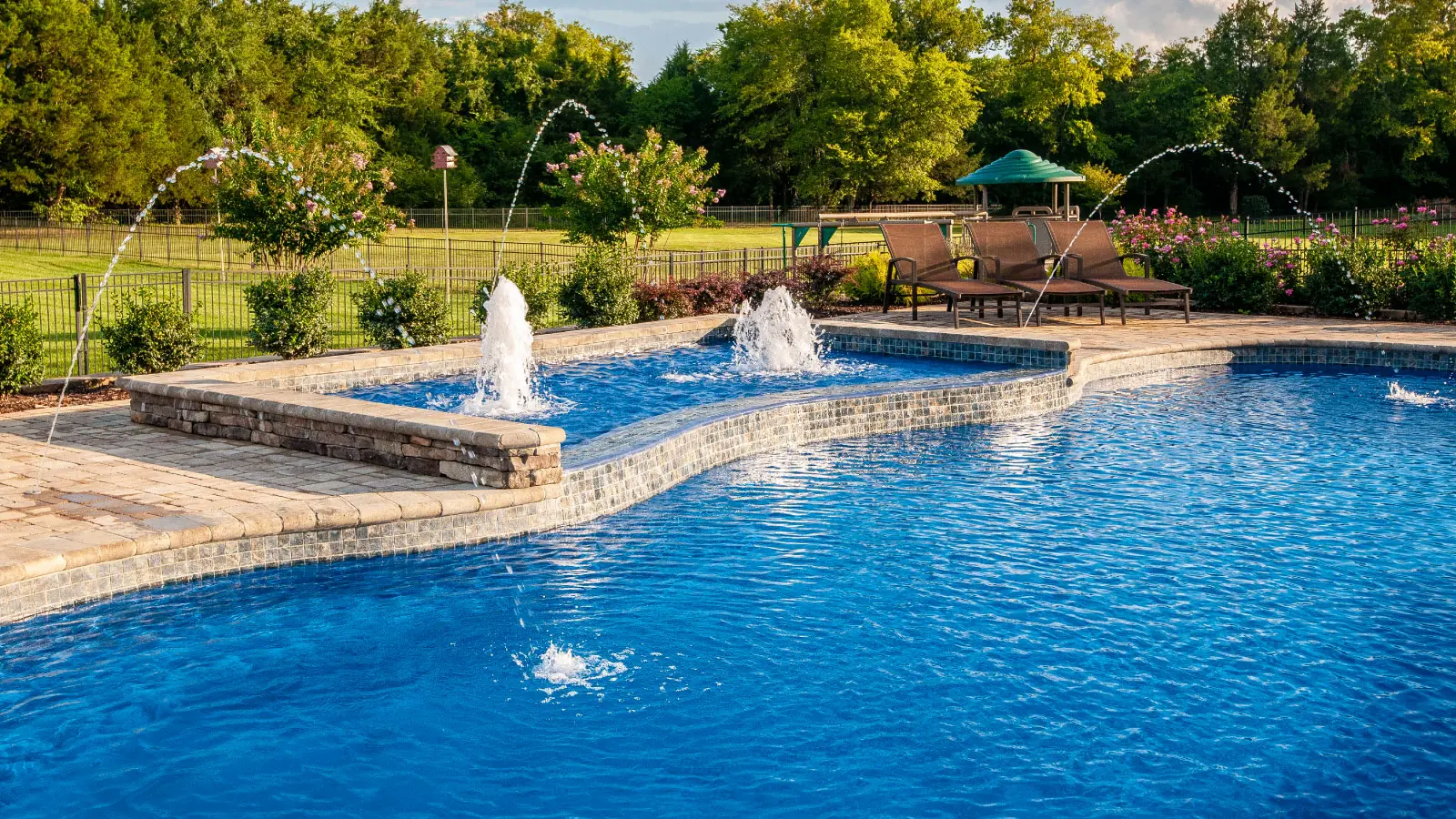 Transform Your Backyard into a Luxurious Oasis: Elevating Your Pool with Water Features, Landscaping, and Fencing